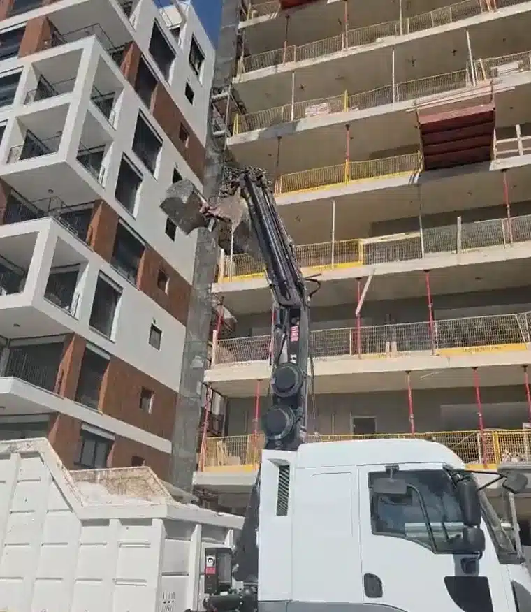 משאית מנוף מעמיסה חומרים ליד בניין, השכרת ציוד וגידור אתרים